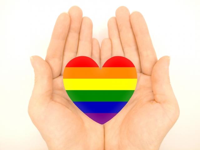 レインボーカラーのハートを手に持つ中立的なイメージ写真｜ジェンダーフルイドの多様性と自分らしさを象徴