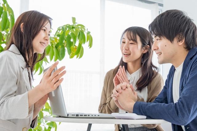 協会スタッフと仲人、相談者の3名が丸テーブルで対話する様子。1名が説明し、2名が傾聴する構図で、協会との連携による丁寧な相談支援を象徴する写真。