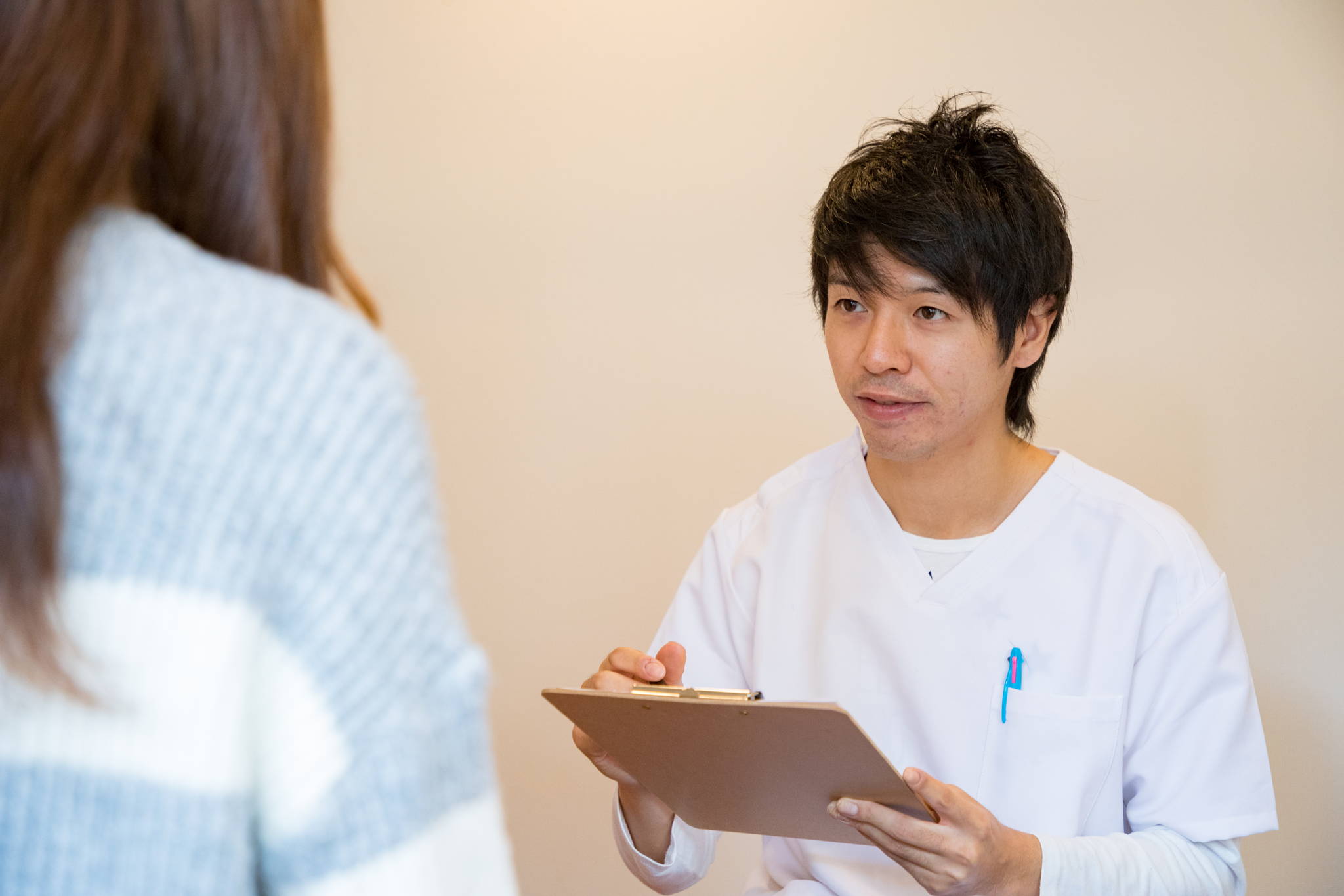 院長が問診票を手に、患者さまと向き合って話を聞いている様子