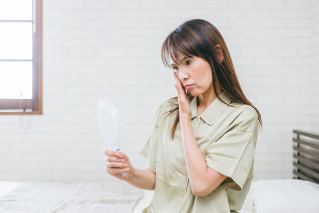 鏡をみて肌を気にする女性