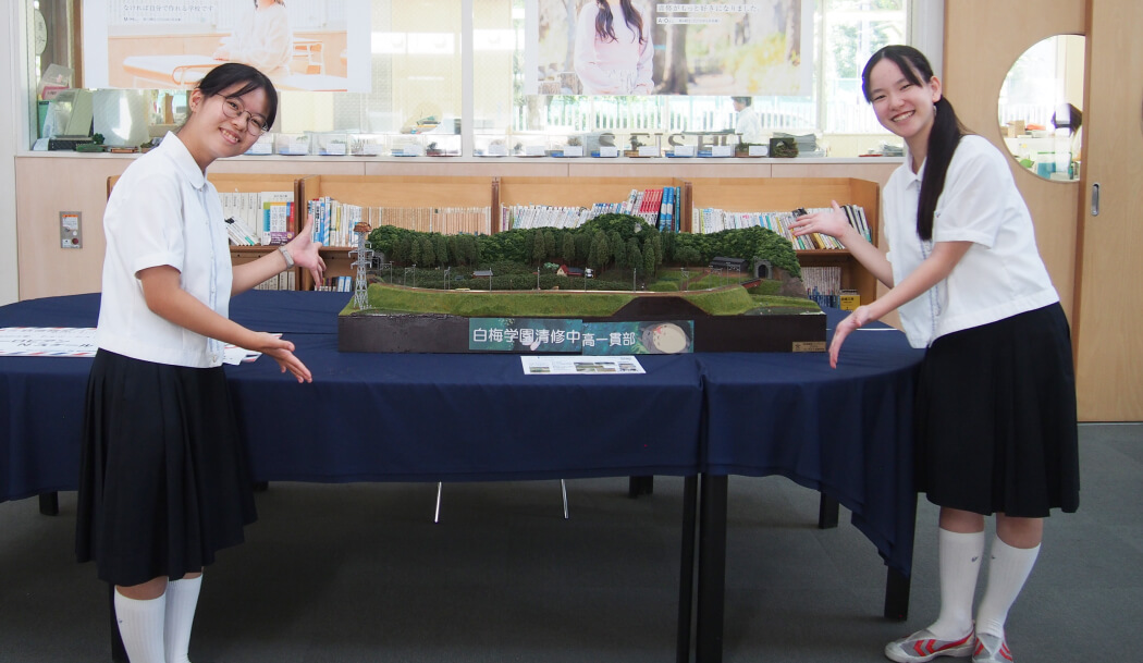 二人が所属する鉄道模型部は数々の大会で受賞するほどの実力。二人も携わった模型の前で撮影