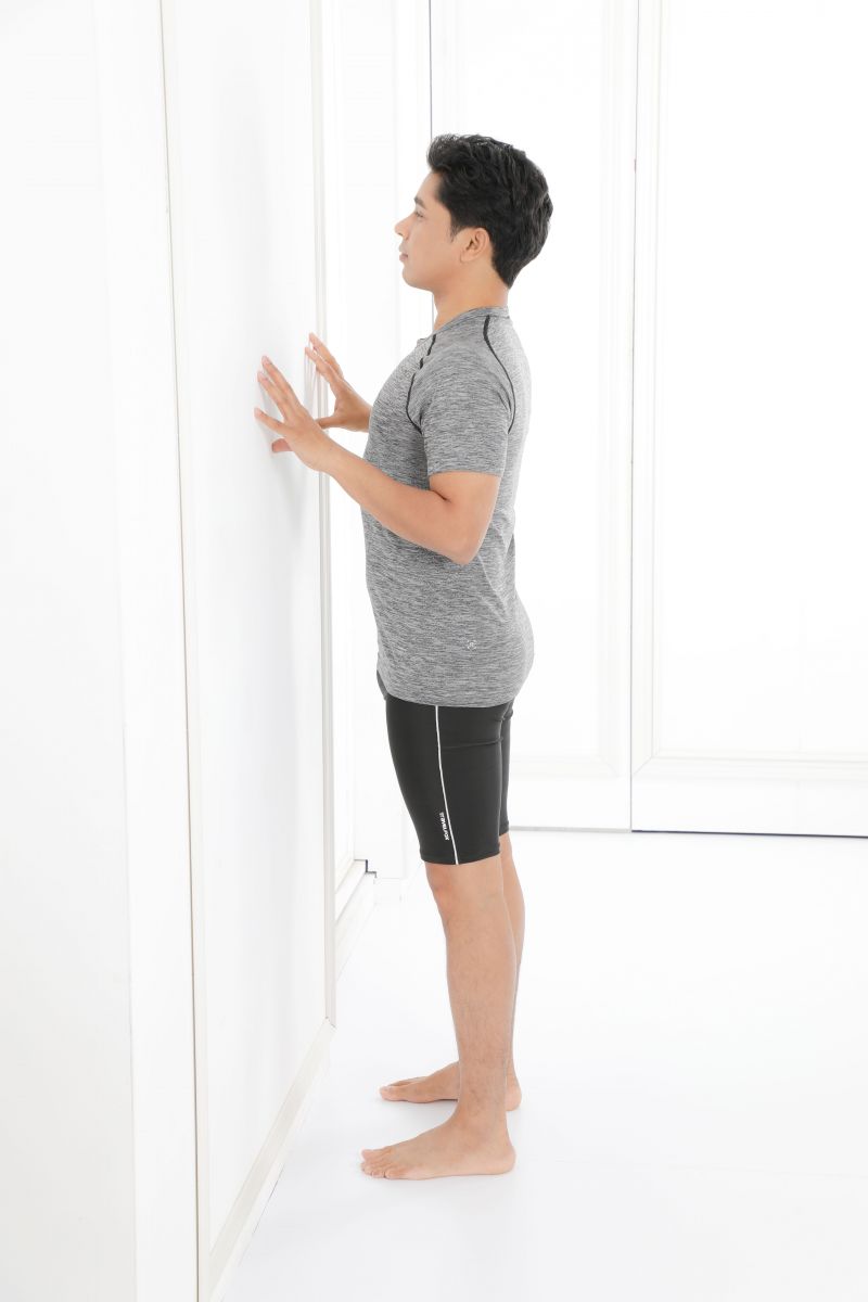 面向牆壁,約距離30公分。手保持在胸前高度,用指尖輕觸牆壁。