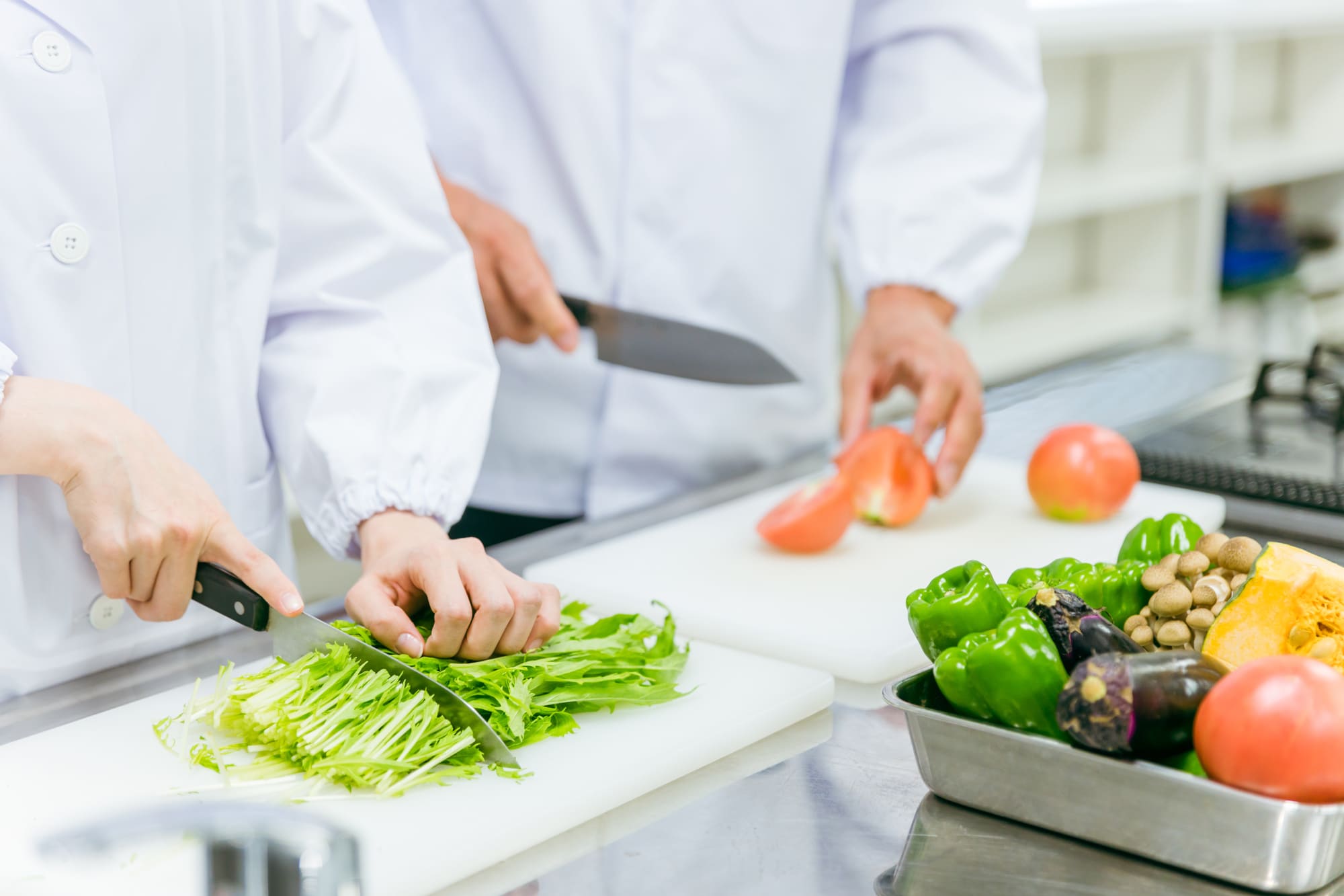 野菜を切っている2人の調理師の手元