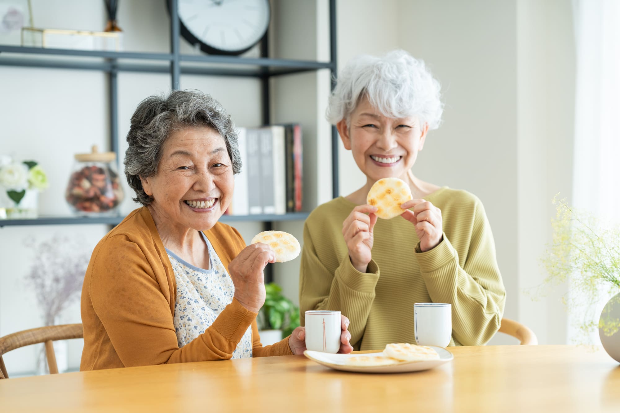 友人とせんべいを食べるシニア女性