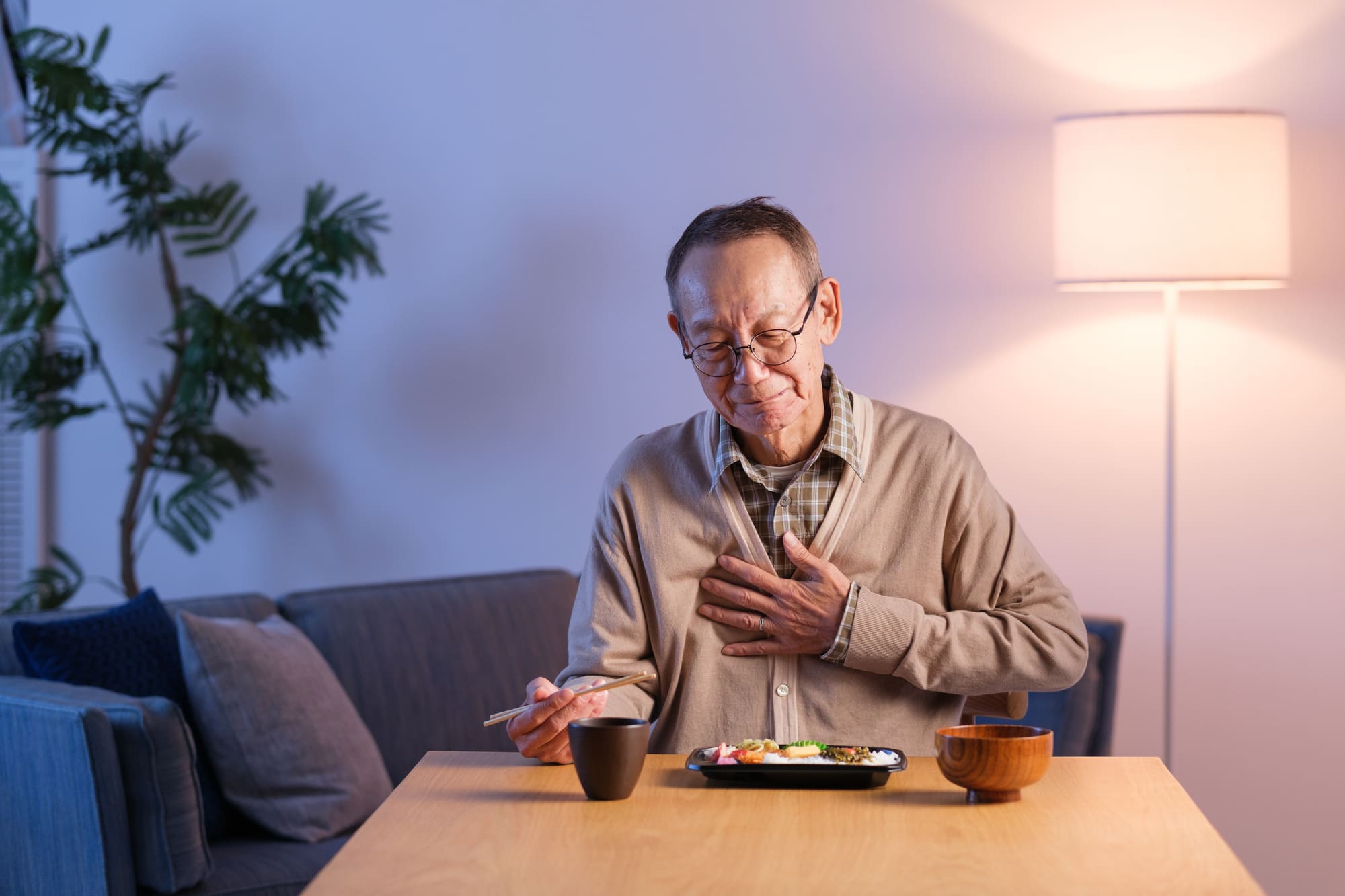 食事中に胸を押さえるシニア男性