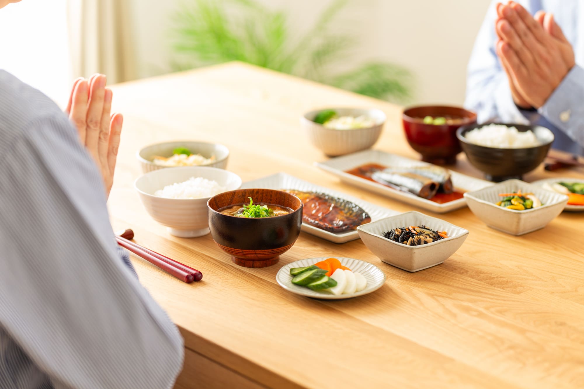 和食の朝食の前で手を合わせる夫婦