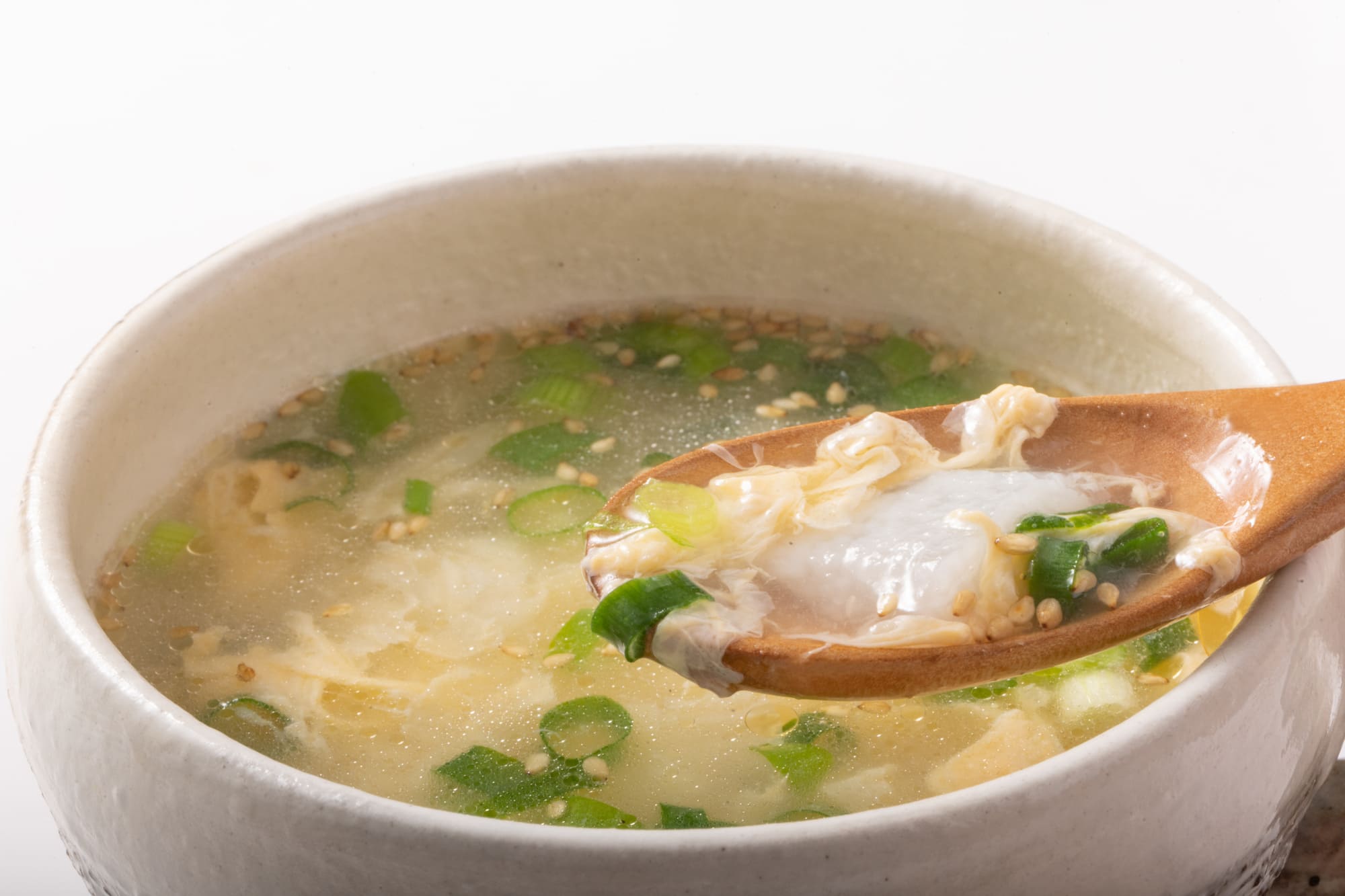 白い器に盛られた溶き卵と白菜のスープと、それをすくう木のスプーン