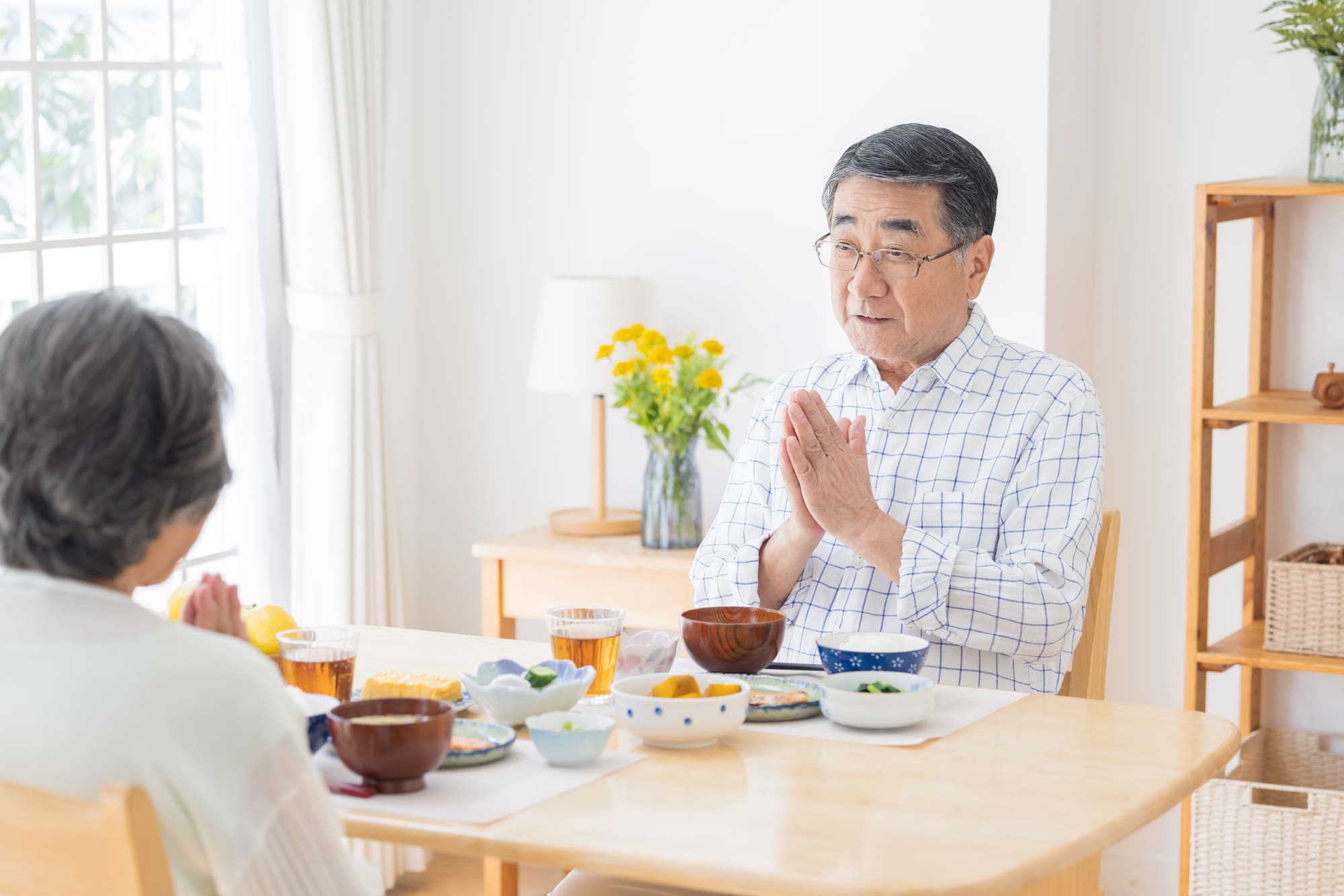 テーブルで向かい合って食事をするシニア夫婦