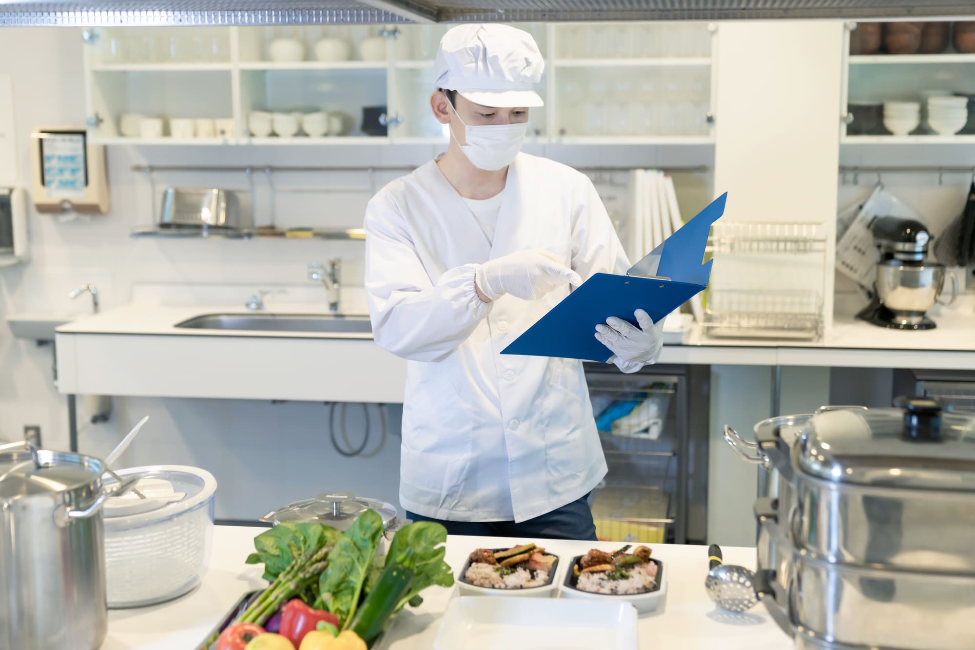 厨房でファイルを指さし確認している男性調理師