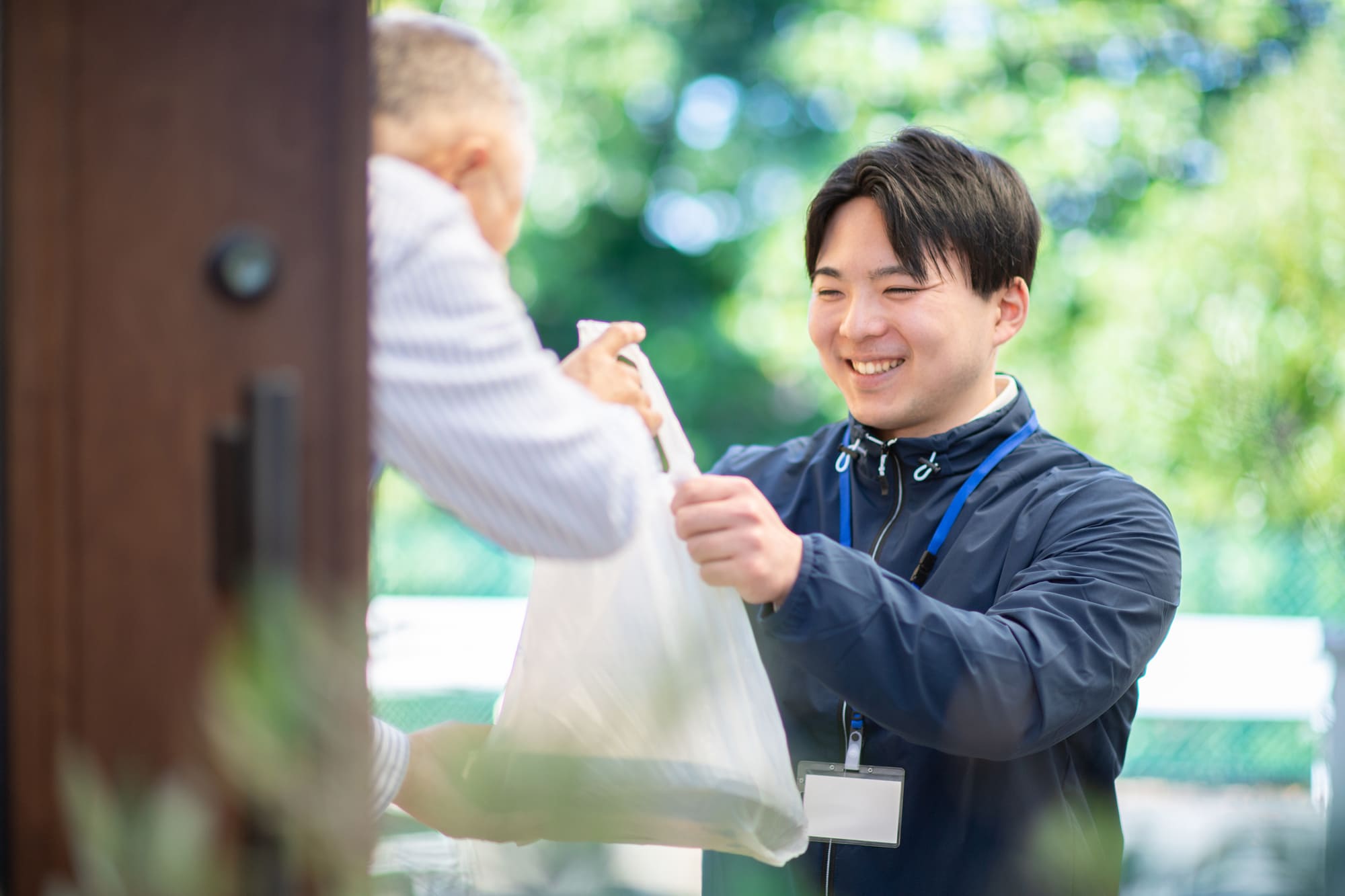 弁当を手渡ししている配達員