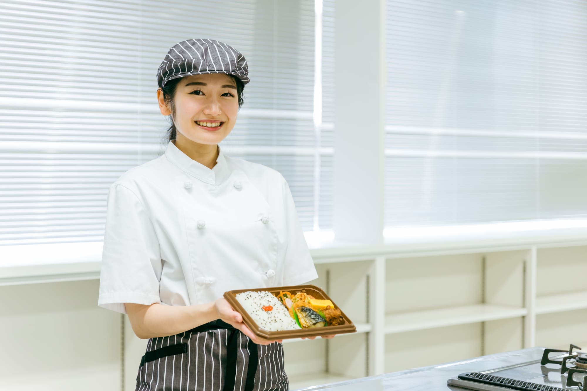 弁当を手に持った女性調理師