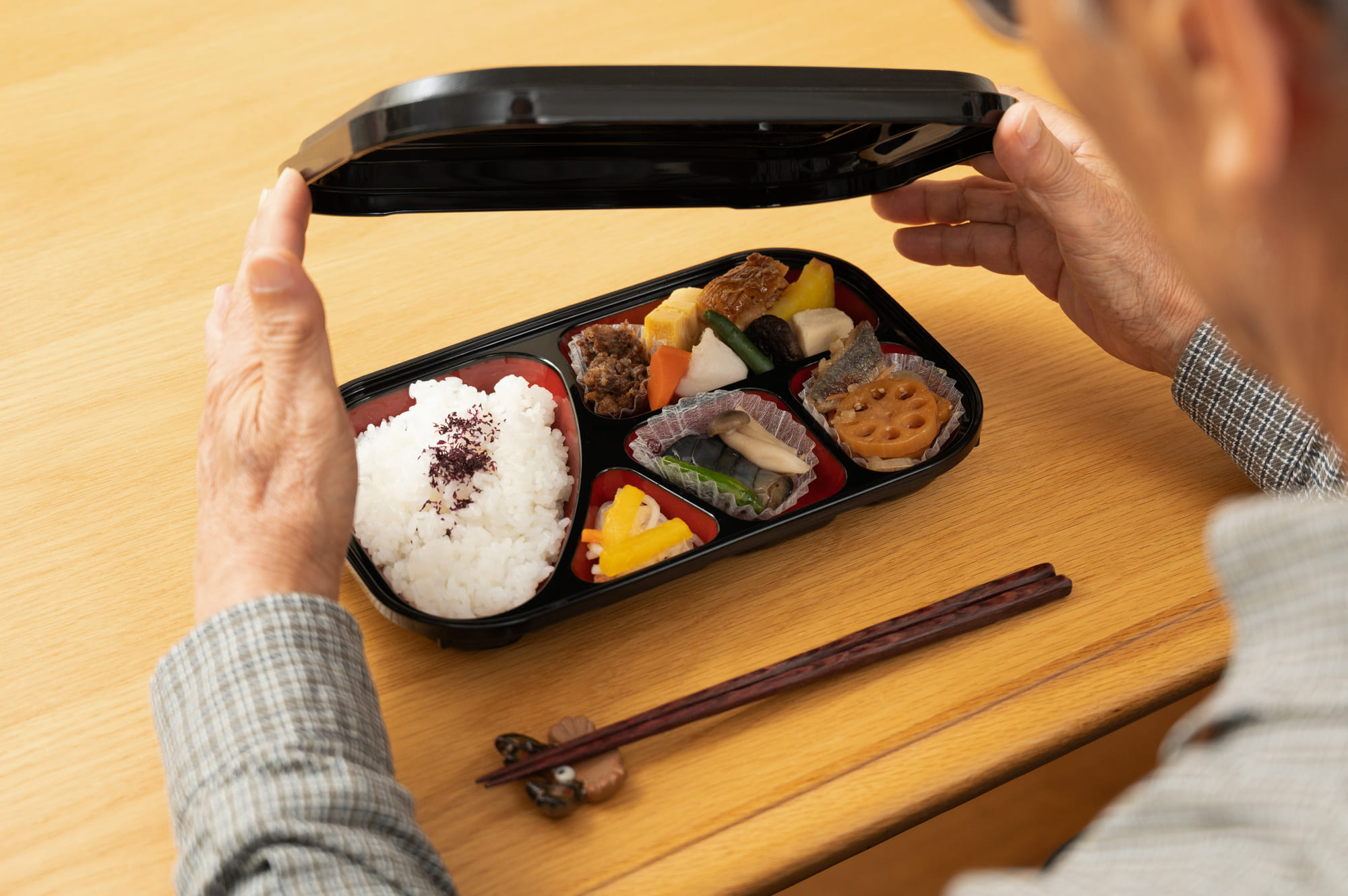 弁当のふたを開けている男性の手元