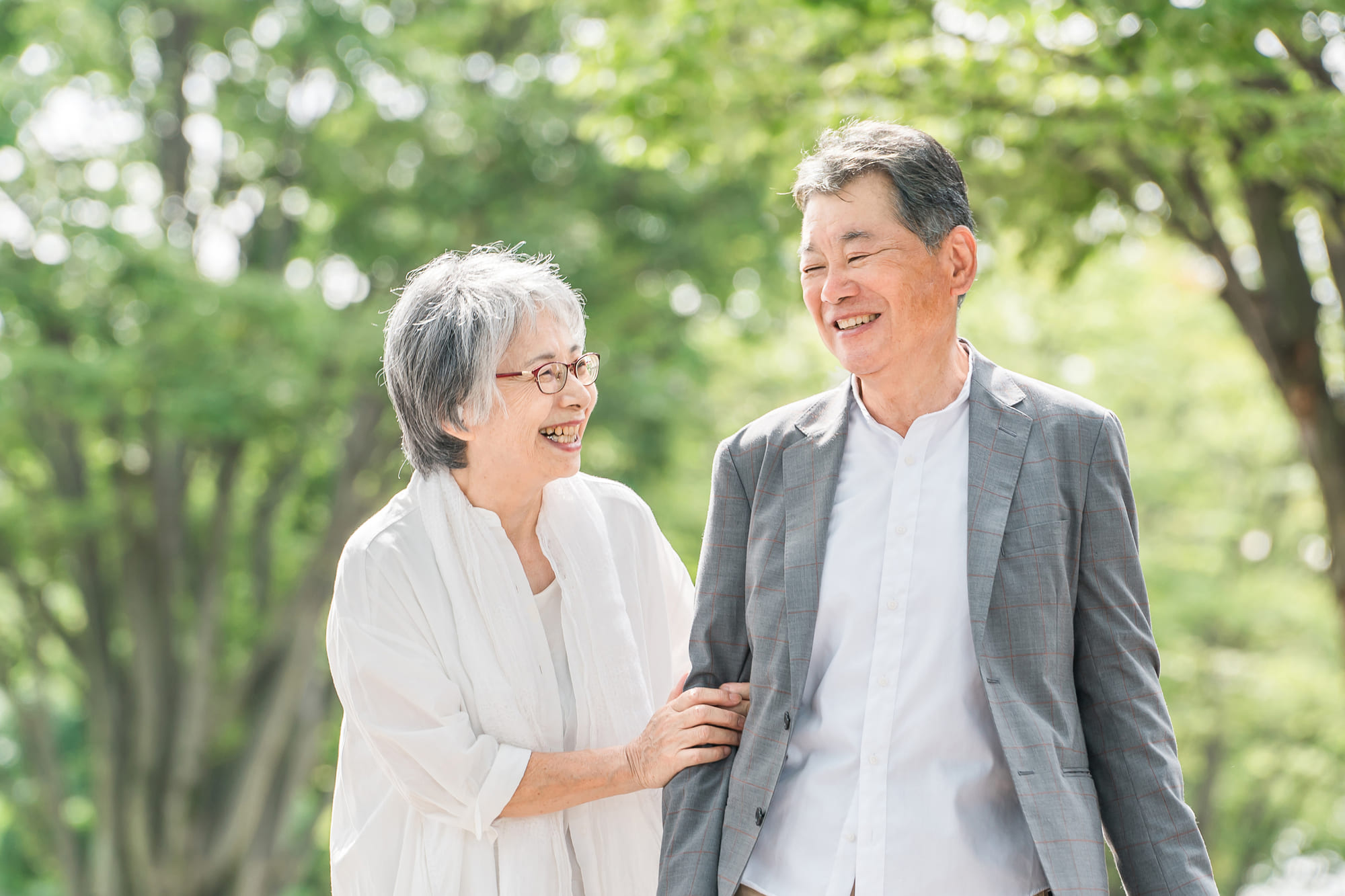 寄り添いながら笑顔で歩くシニア夫婦