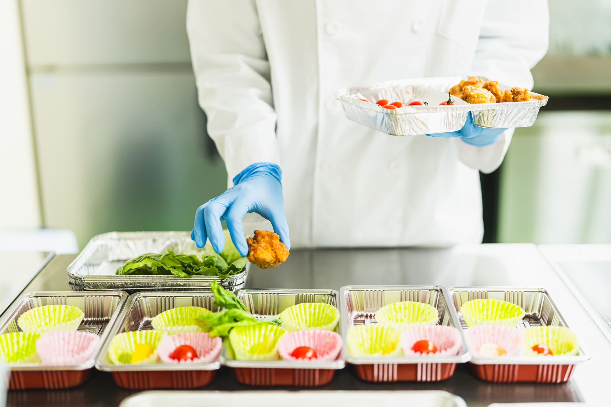 複数のお弁当に惣菜を詰める様子