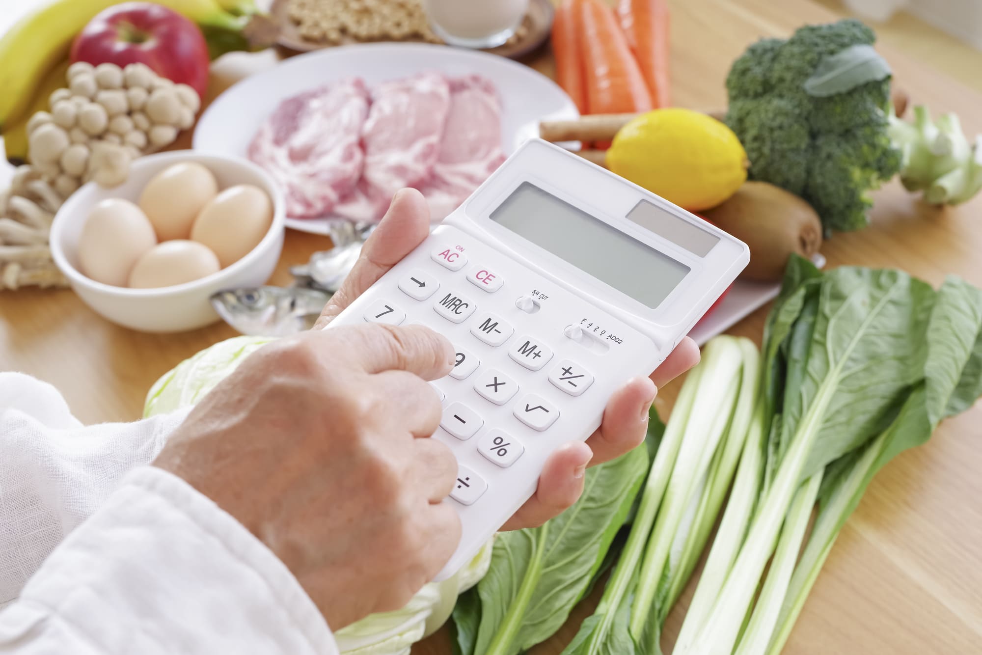 さまざまな食品と計算機を持つ人の手