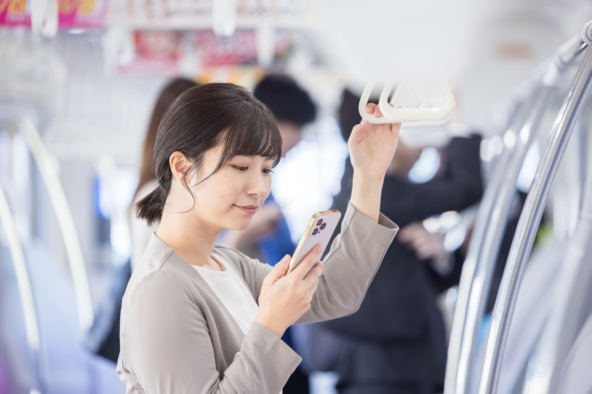 電車の車内でスマホを見る女性
