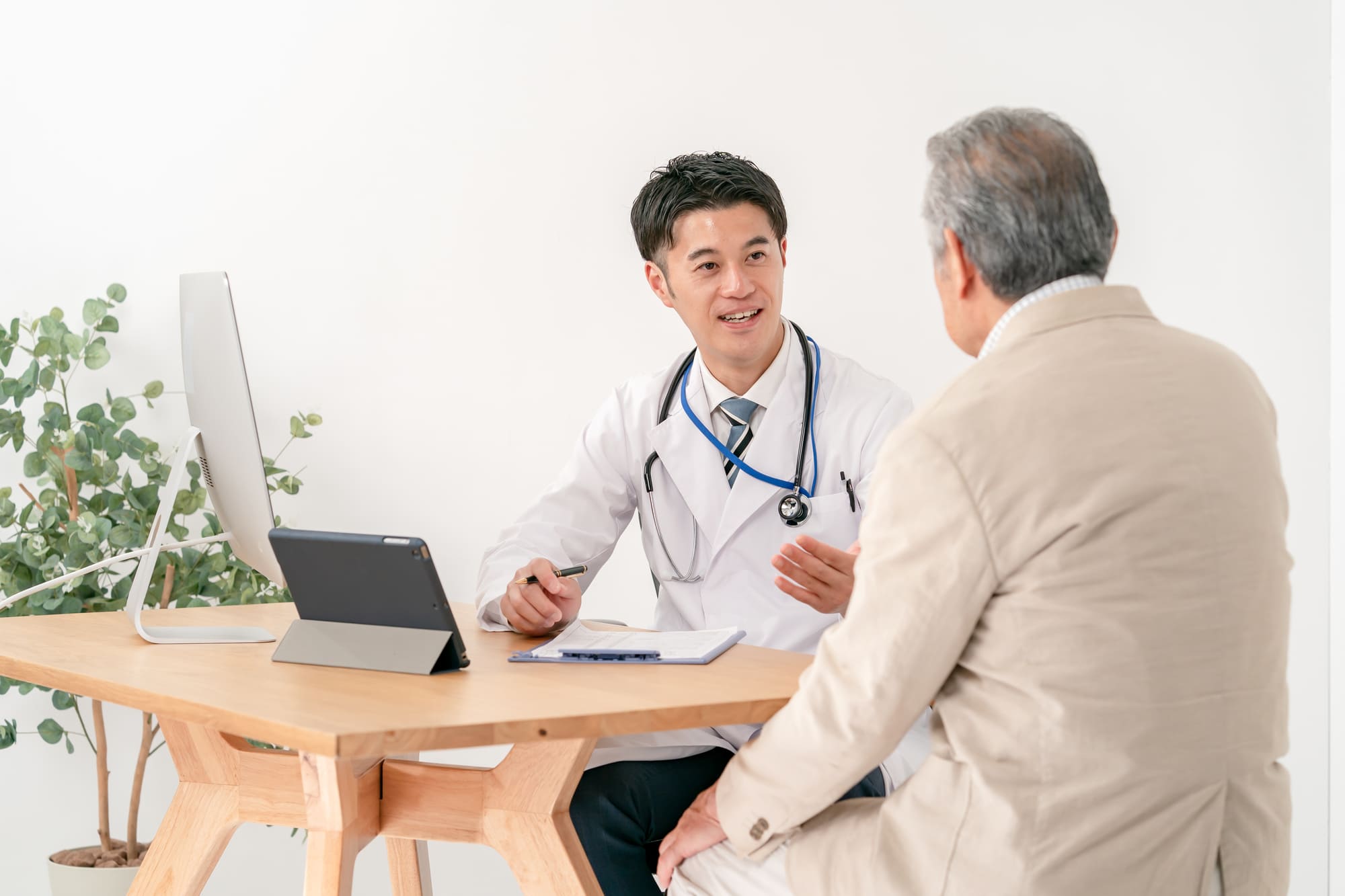 病院で医者の診察を受けるシニア男性