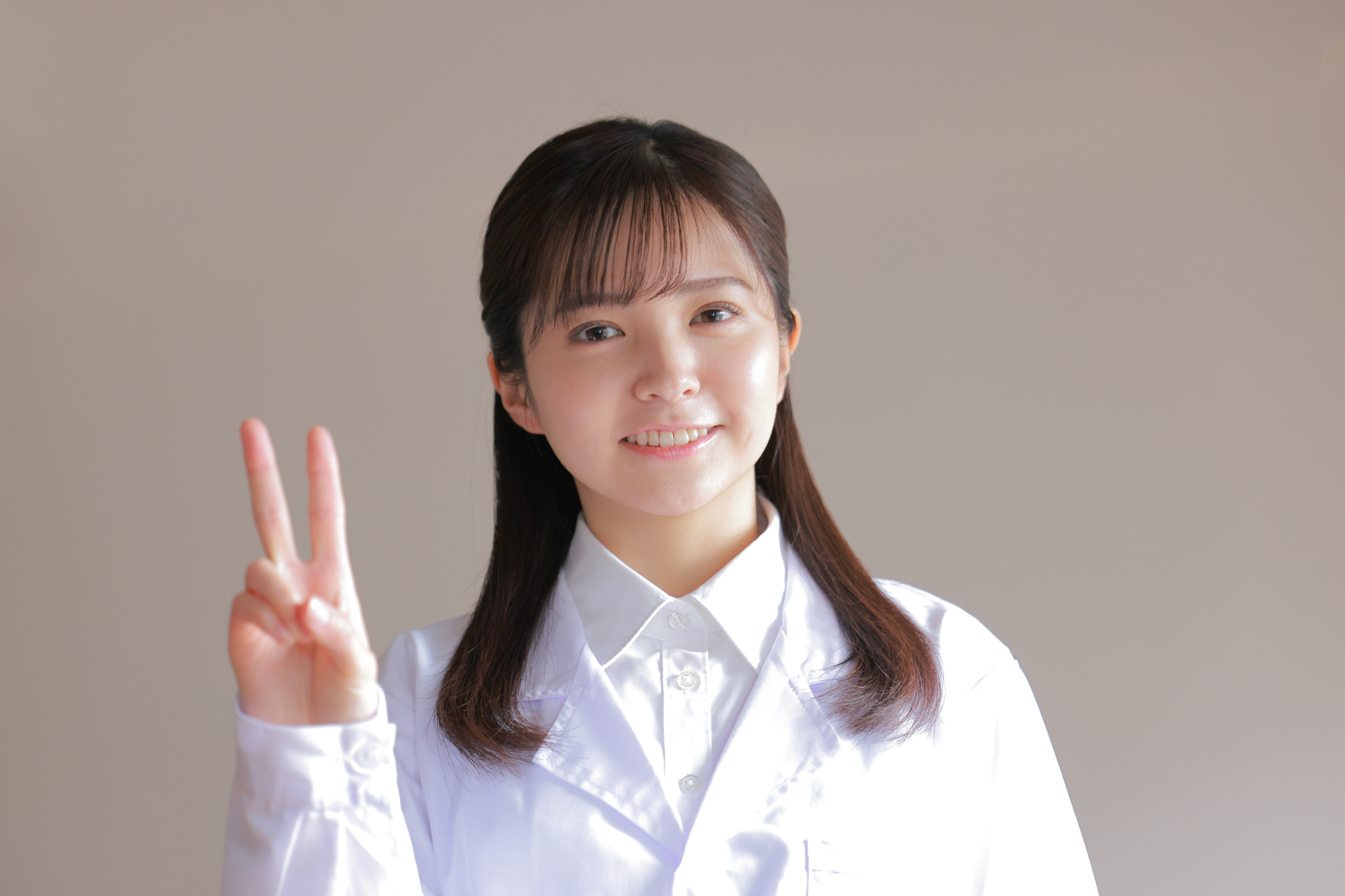 指で2を示す白衣を着た女性