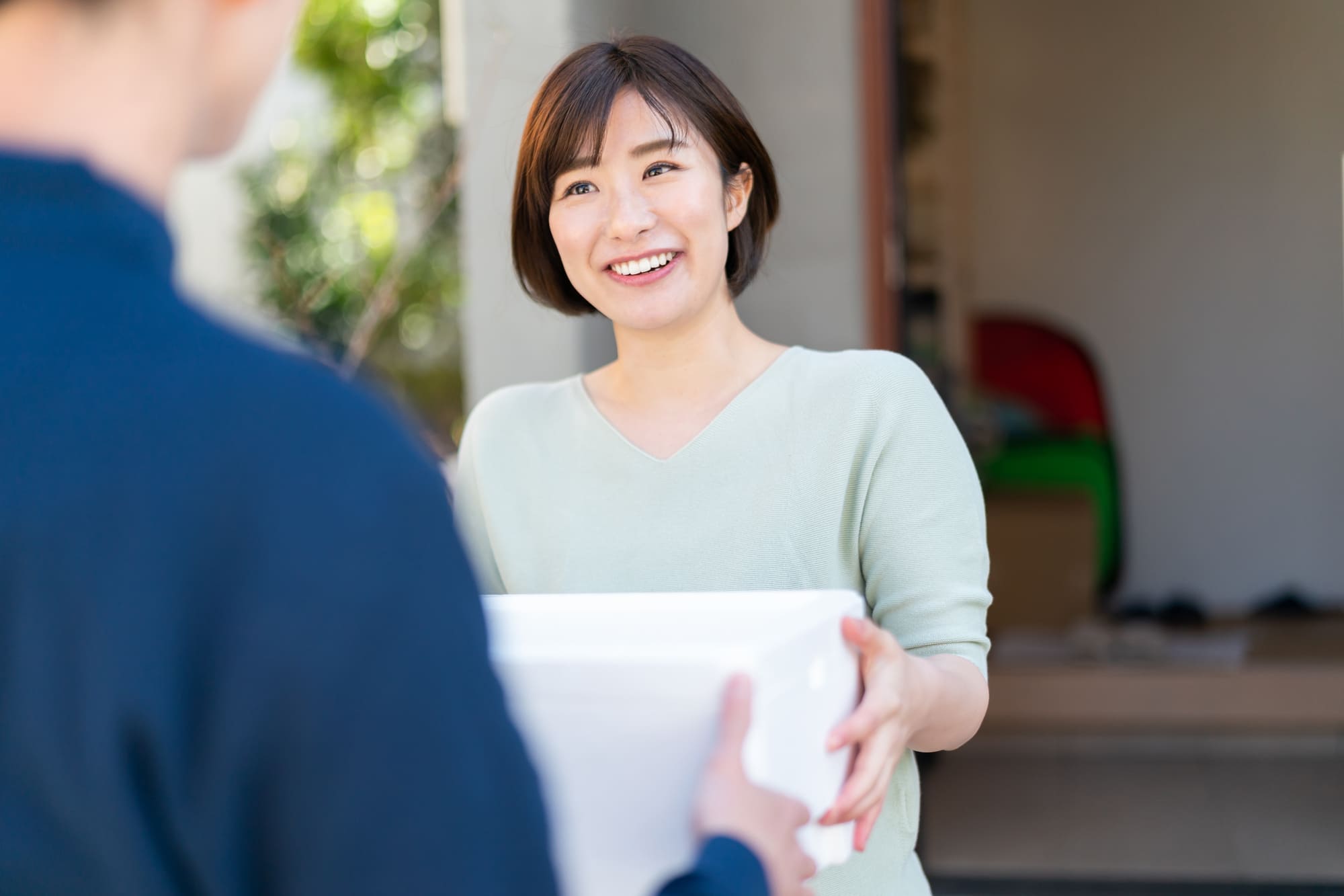 配達員から荷物を受け取る女性