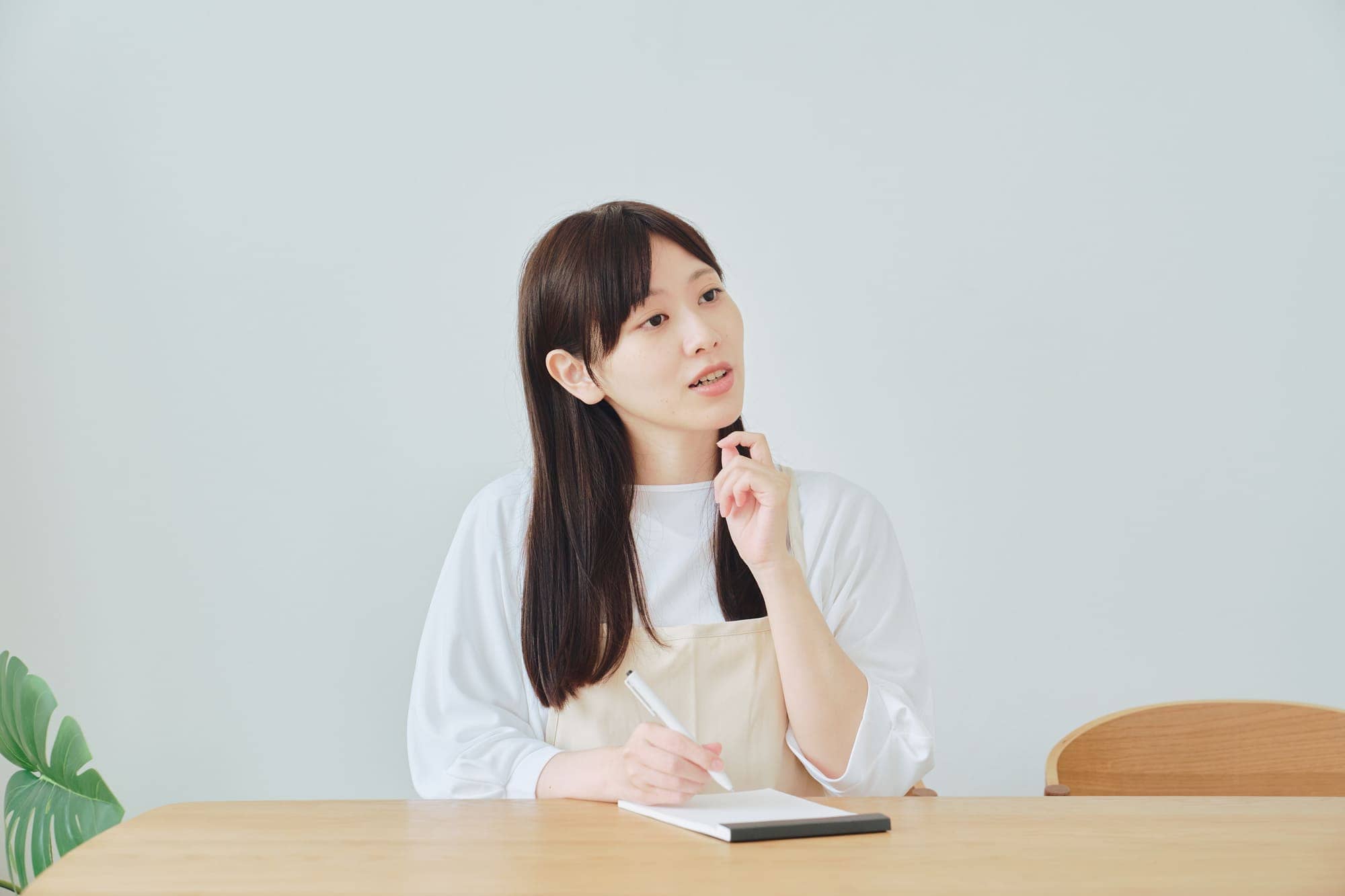 メモを取りながら考えているエプロン姿の女性