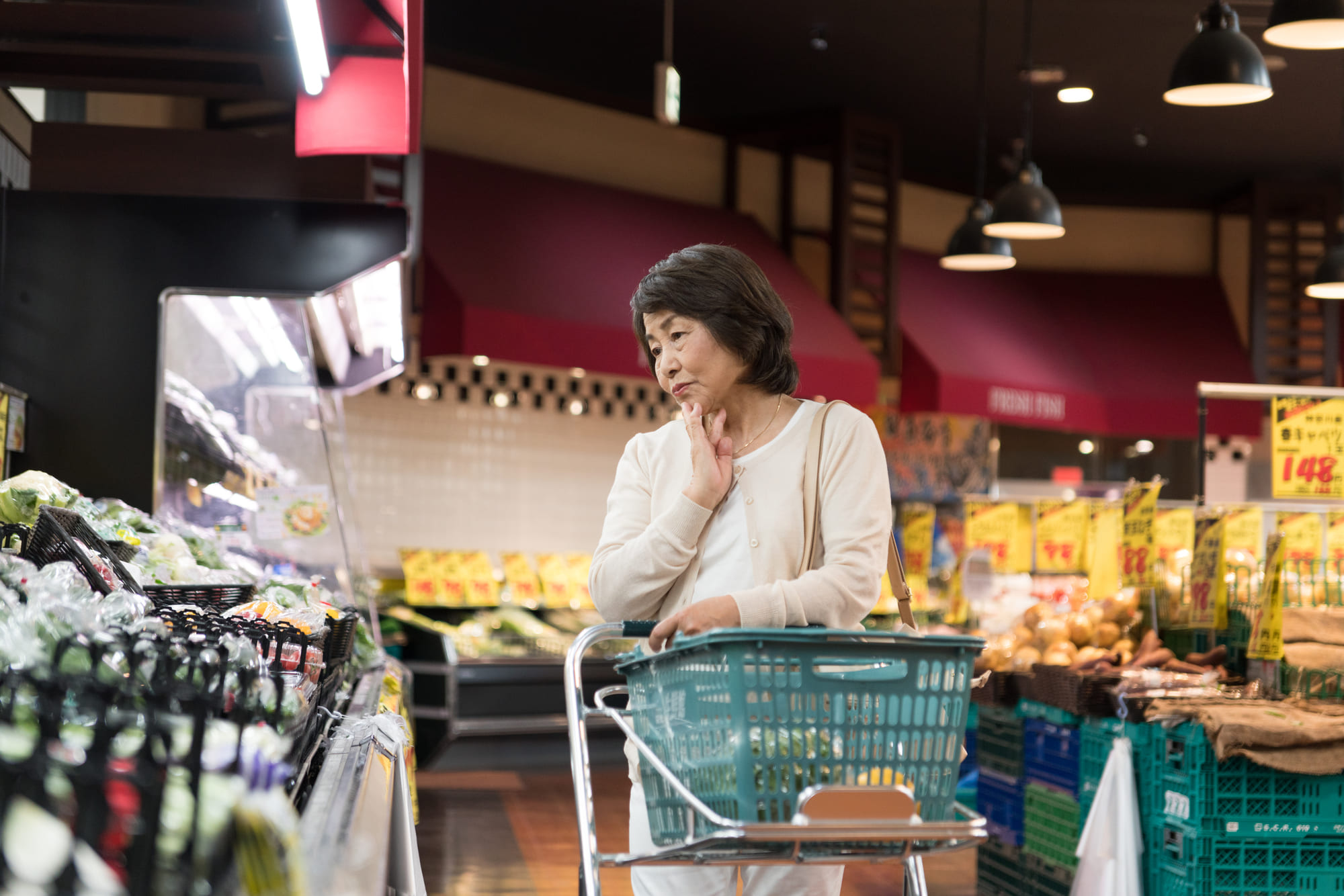 スーパーで悩みながら買い物するシニア女性