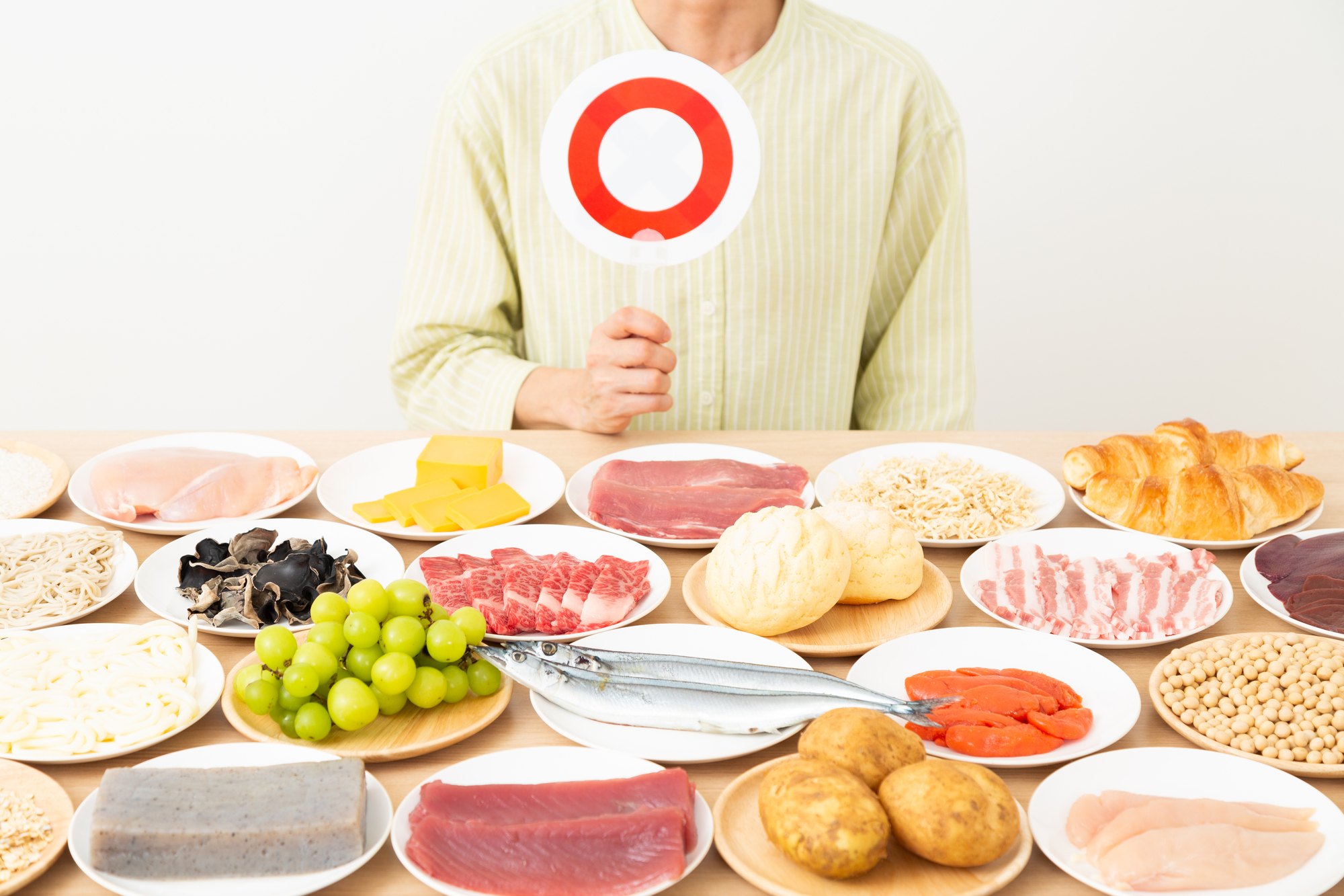 さまざまな食材と丸のプレートを持つ女性