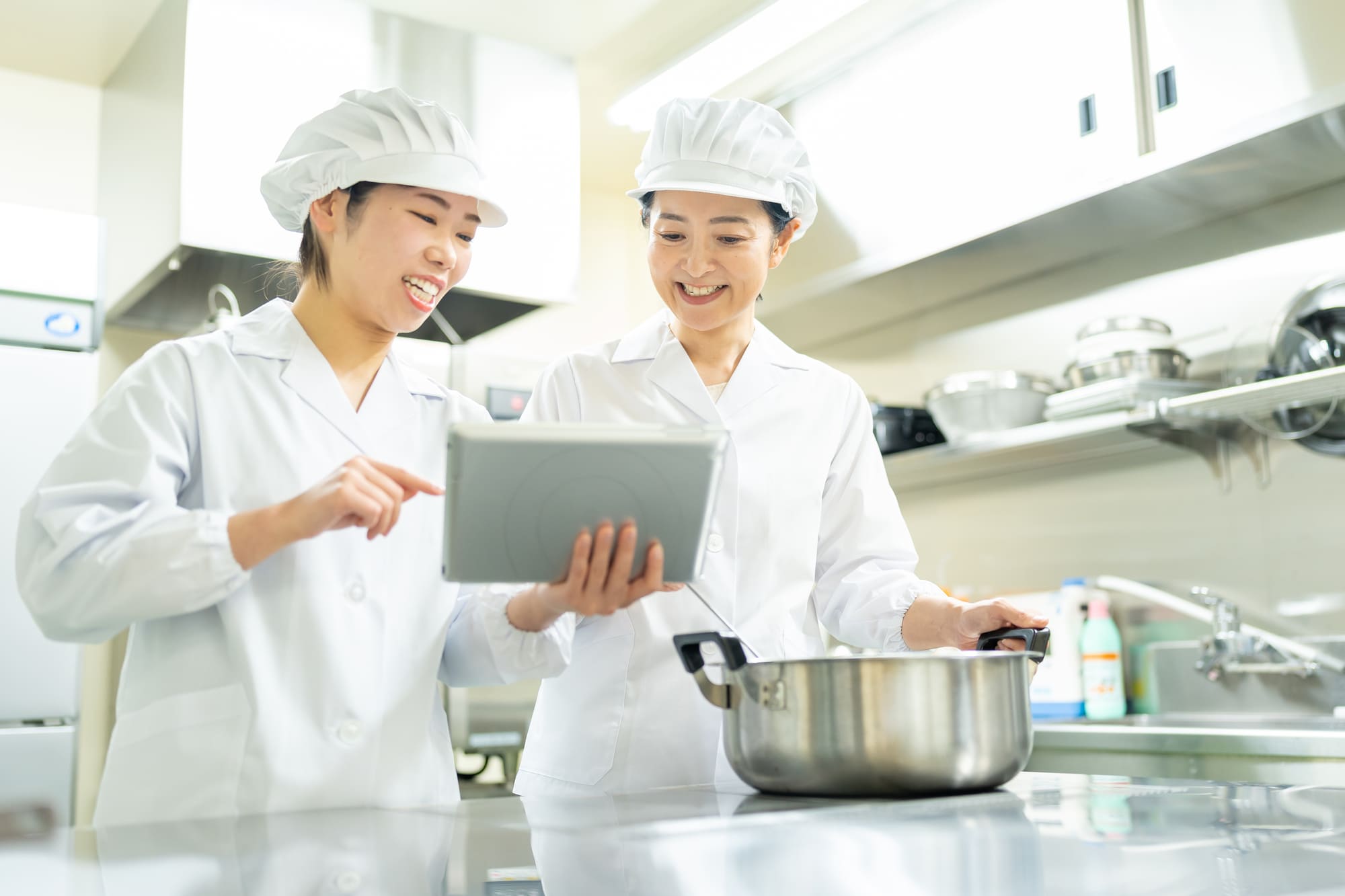 厨房でタブレットを見ながら話をする2人の調理師