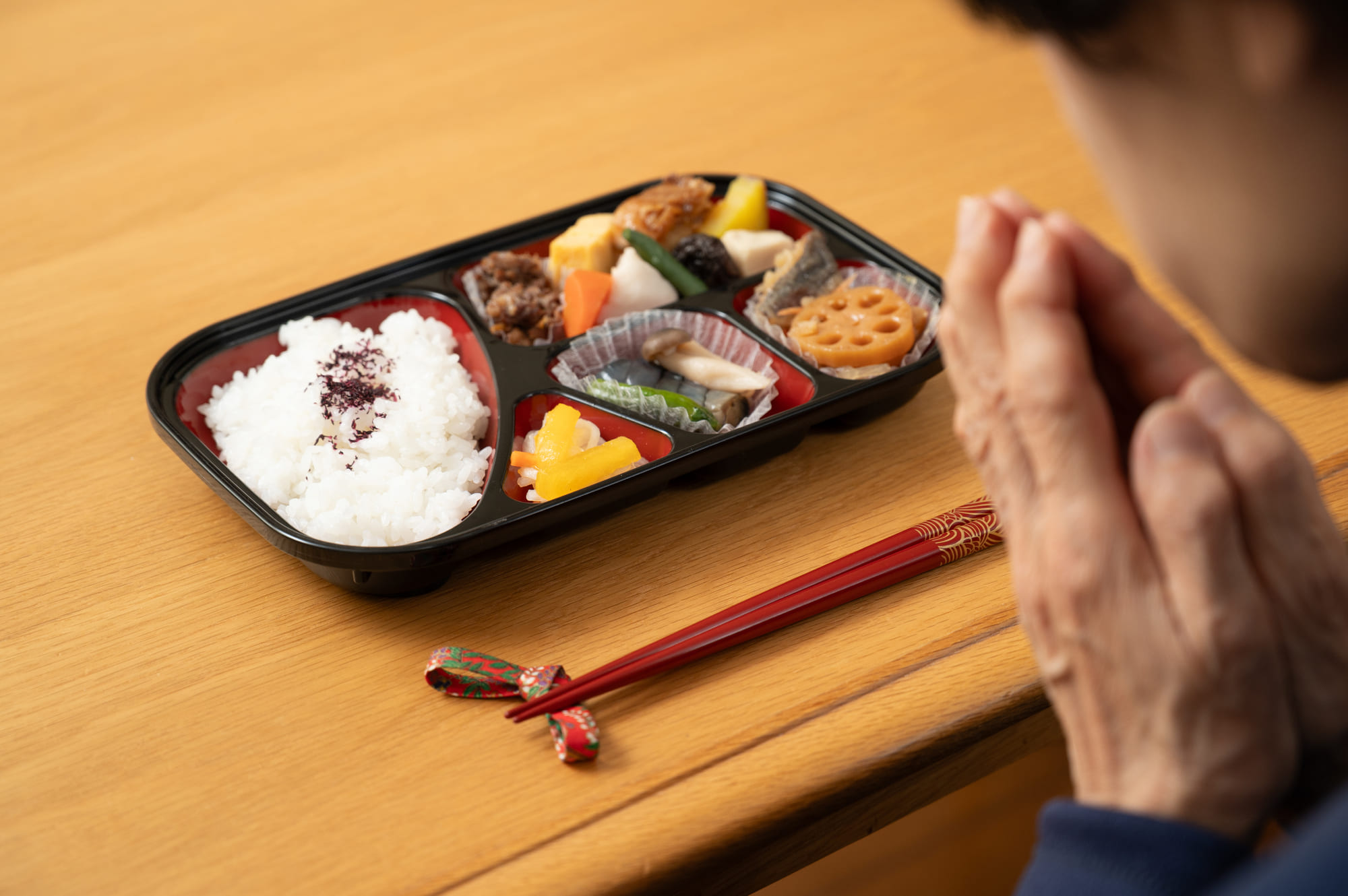 宅配弁当を食べる前に手を合わせている男性
