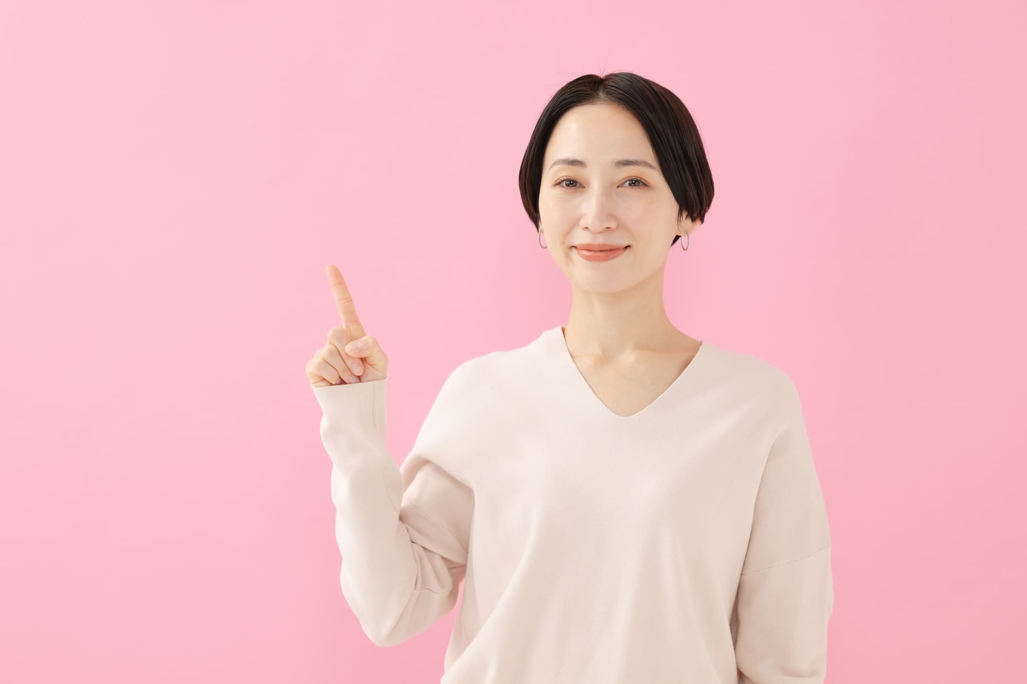 人さし指を上に向けてこちらを見る女性