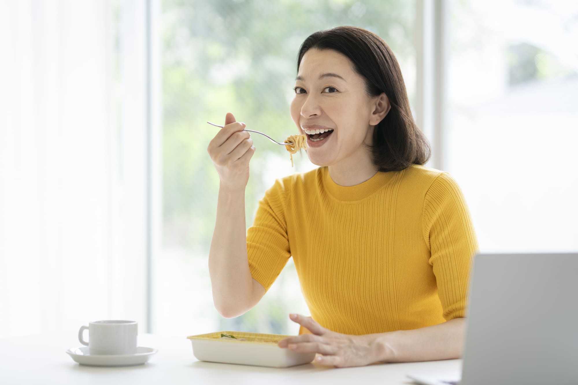 オフィスで弁当を食べる笑顔の女性