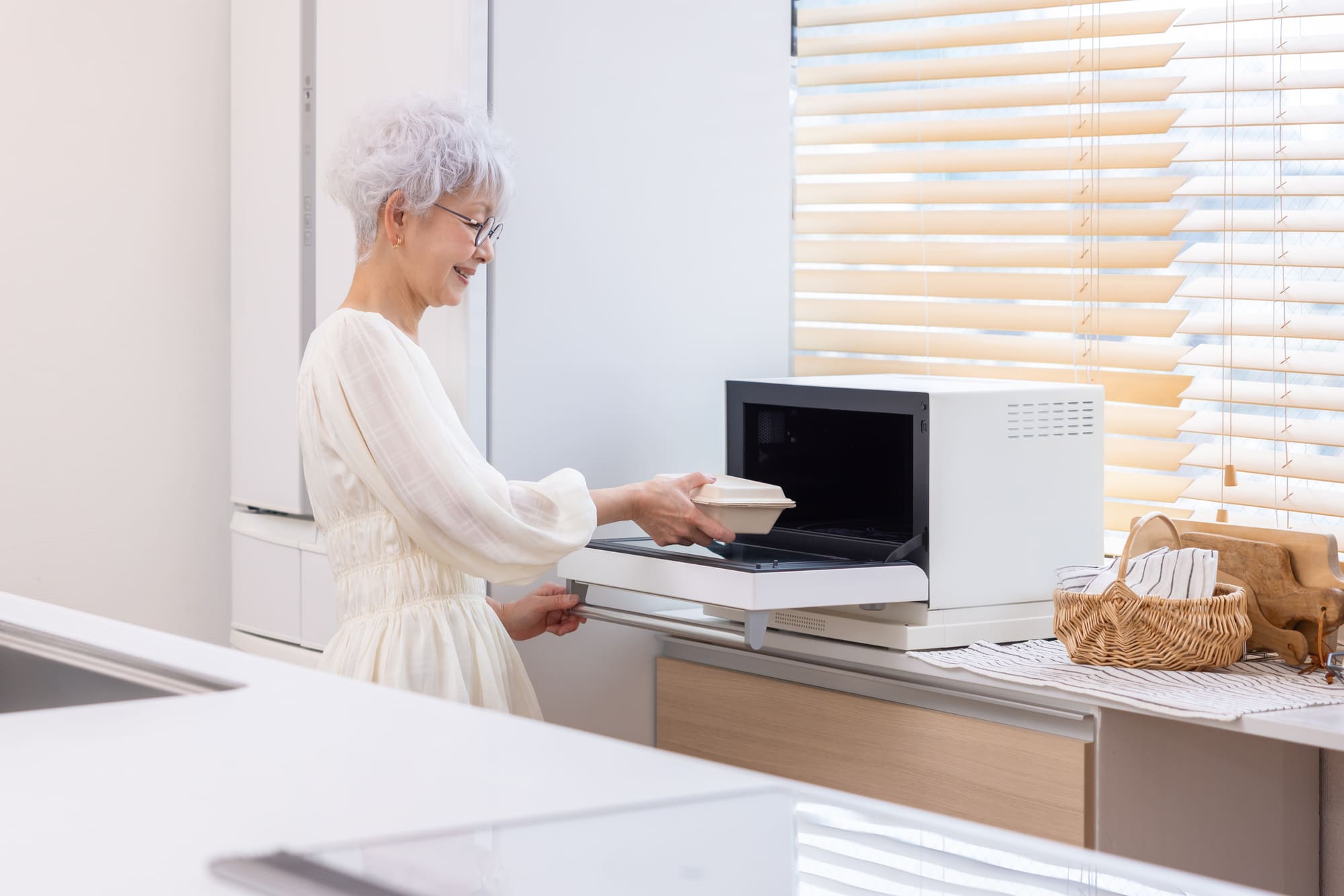 電子レンジで宅配弁当を温めるシニア女性