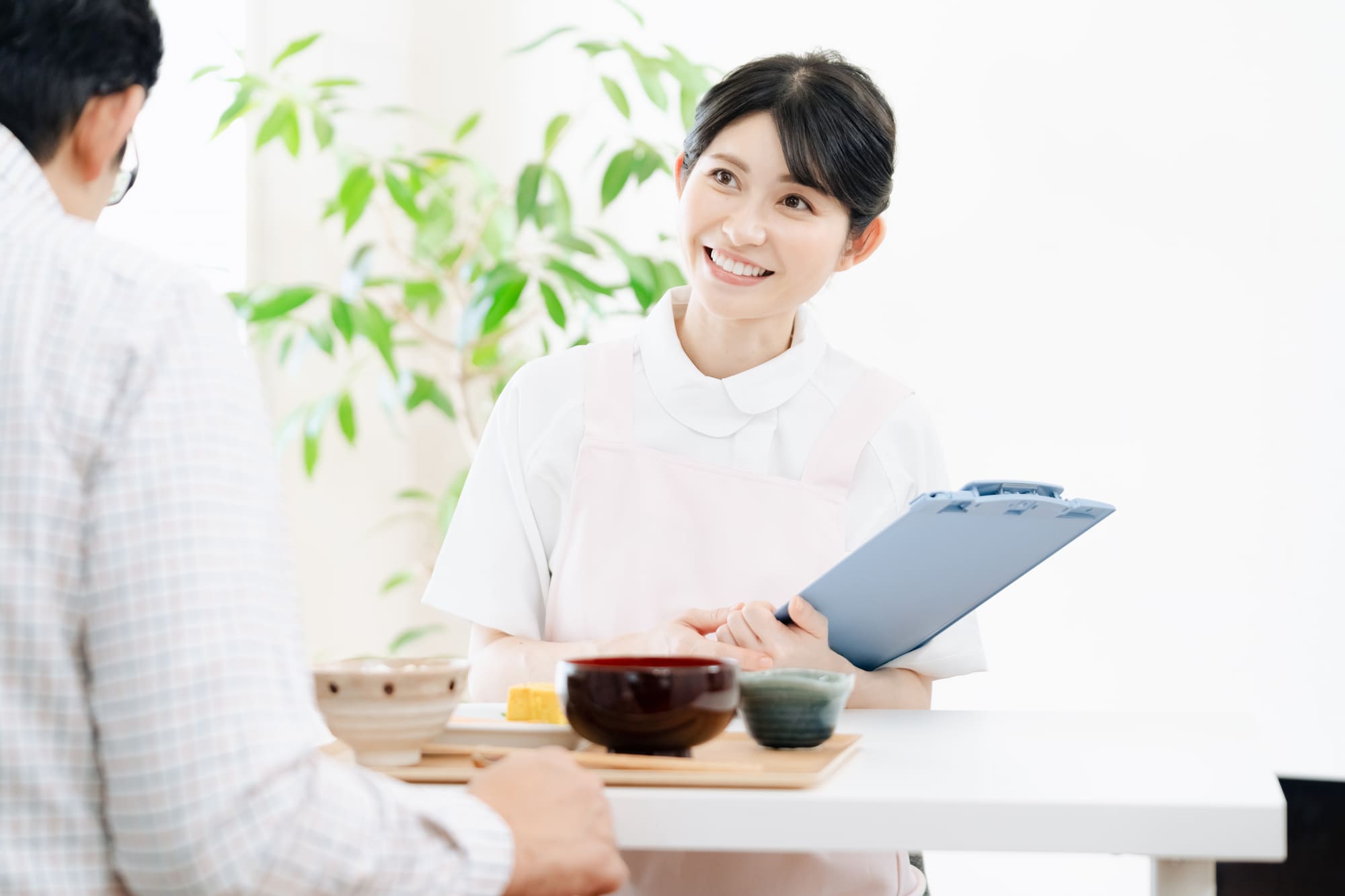 バインダーを持ち、食事を見ながら栄養指導をする女性