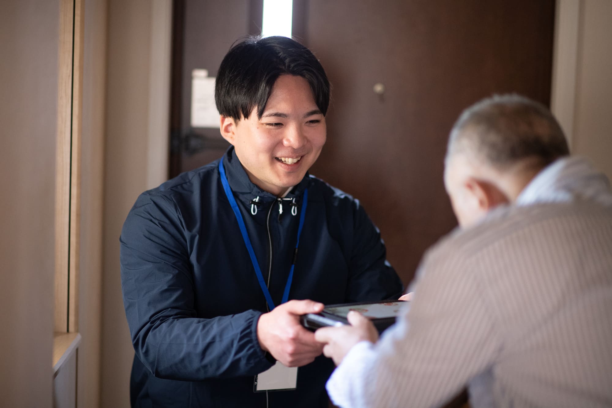 お弁当を高齢の男性に手渡しする男性配達員
