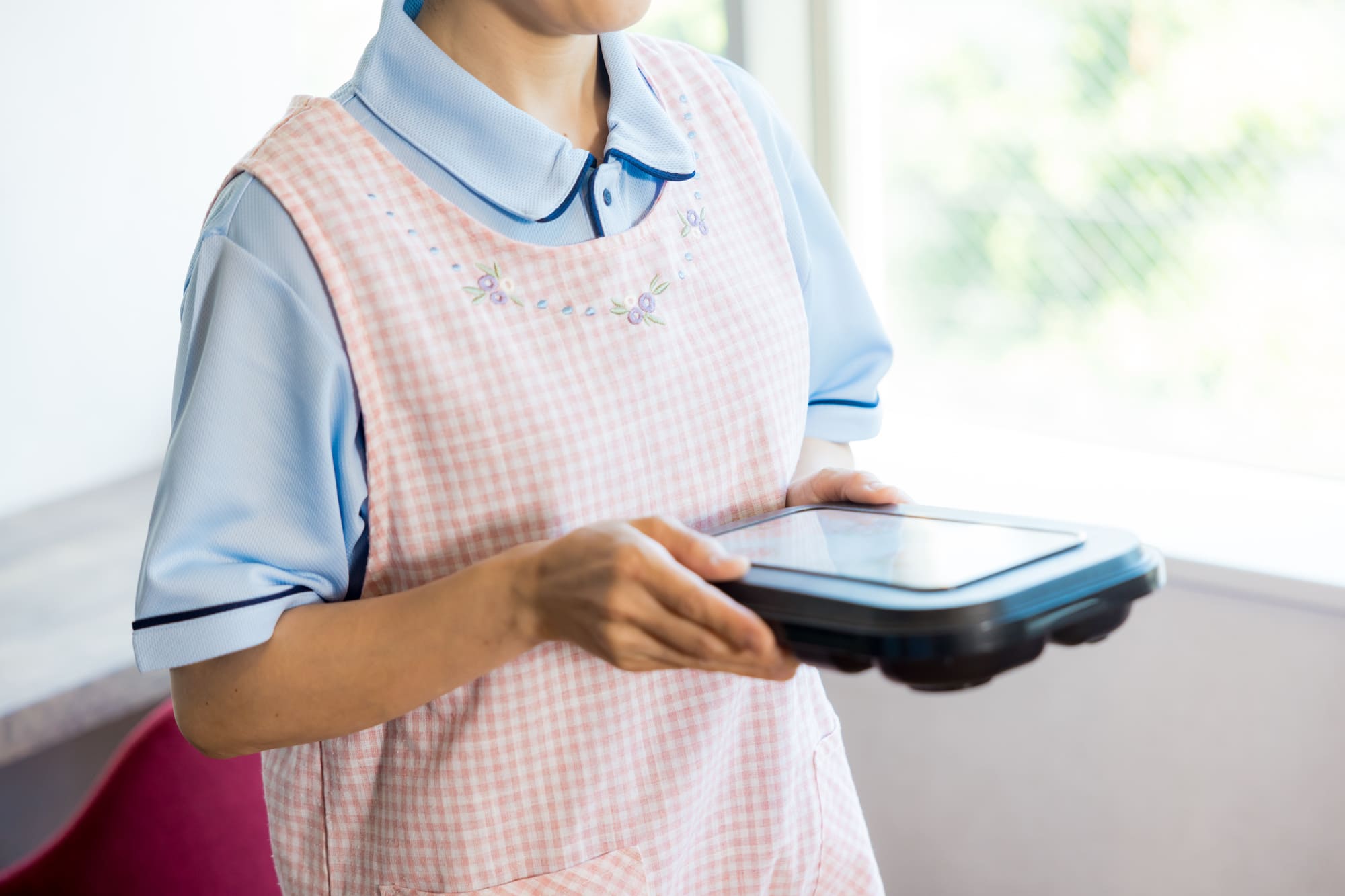 お弁当を手に持っているエプロン姿の女性