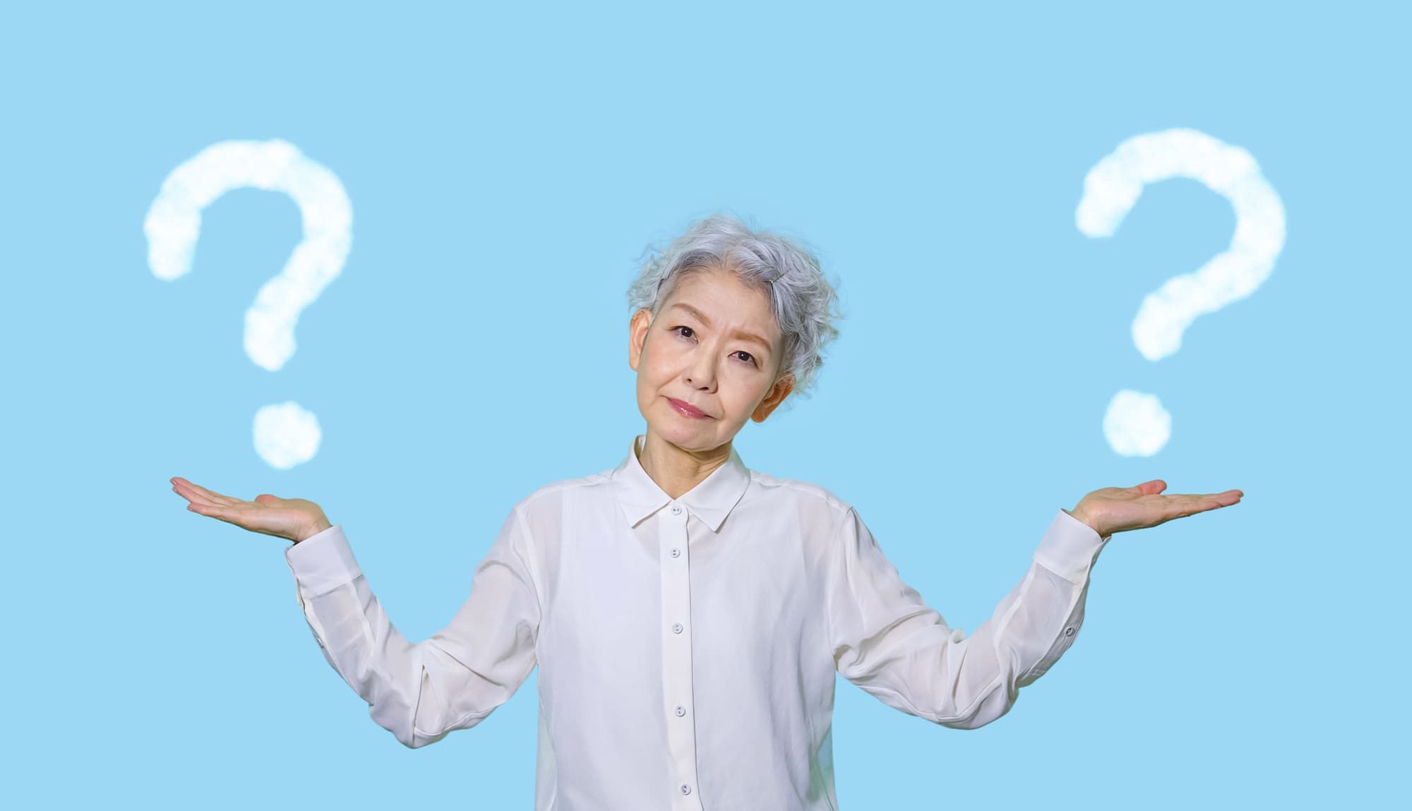 「？」マークを背景に、両手を広げて上に向けるシニア女性