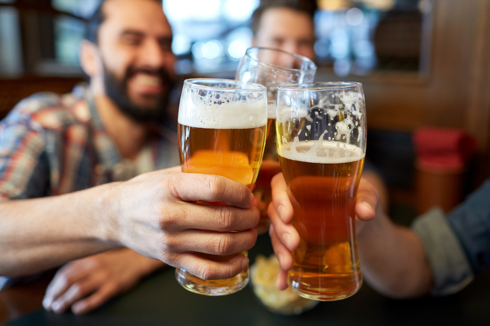 people, men, leisure, friendship and celebration concept - happy male friends drinking beer and clinking glasses at bar or pub