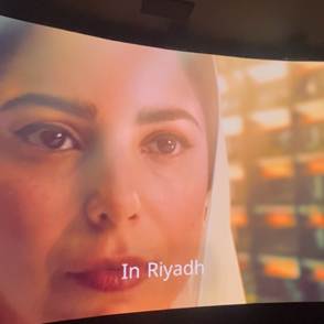 A person's face on a curved screen
Description automatically generated