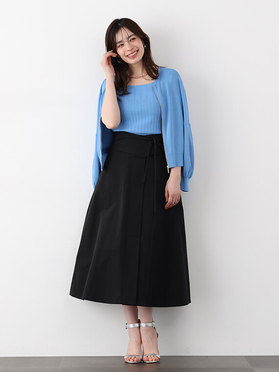ブルー半そでニットに黒のフレアスカート、肩に花柄スカーフ