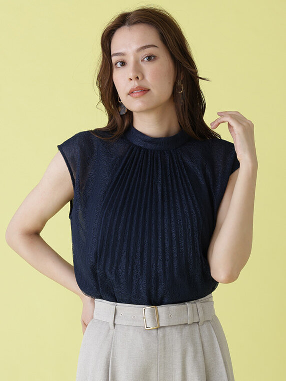 ネイビーのレースハイネックブラウスにベージュのショートパンツ