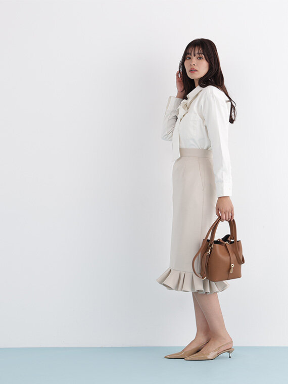 ホワイトデニムシャツにベージュのひざ丈タイトスカート。ブラウンのハンドバッグを合わせてワントーンベージュコーデ。