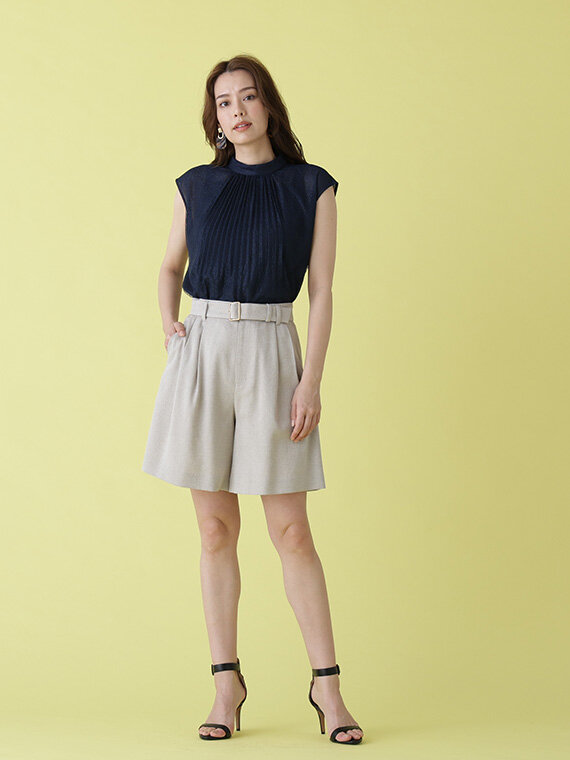 ネイビーのレースハイネックブラウスにベージュのショートパンツ