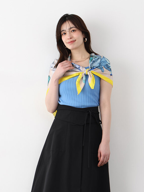 ブルー半そでニットに黒のフレアスカート、肩に花柄スカーフ