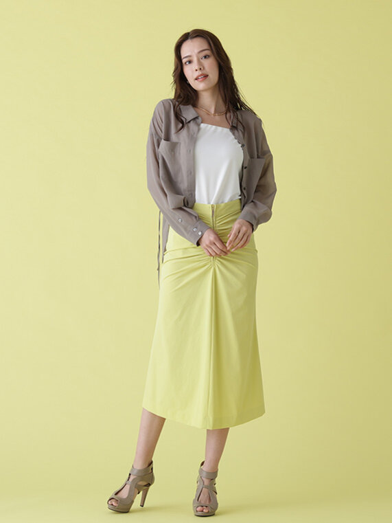 モカカラーのシャツを羽織に、ホワイトのインナーキャミとイエローのタイトスカート