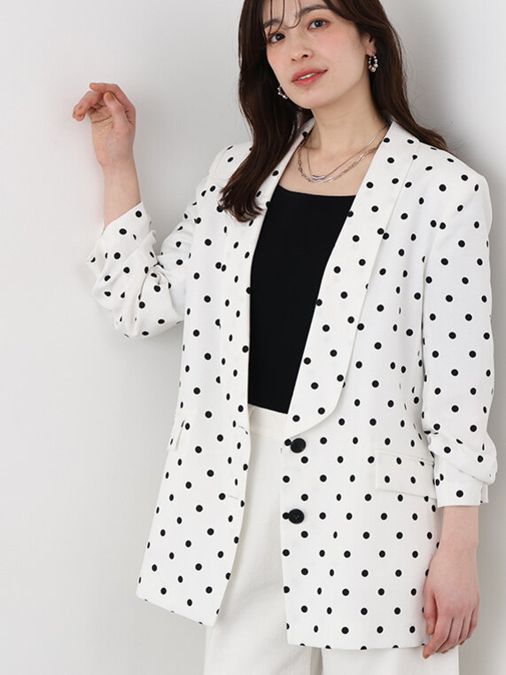 白ベースのジャケット、ブラックのニットトップス、白デニムのパンツ