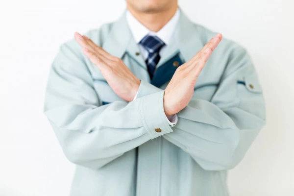 グリーンの作業服を着てバツサインをする男性ビジネスマン