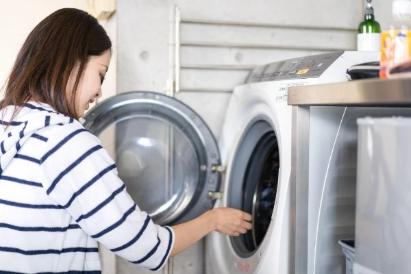 ドラム式洗濯機の中に手を入れている女性の画像