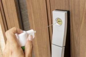 玄関ドアの鍵穴にスプレーで潤滑剤を入れるイメージ