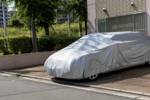 灰色の自動車用ボディカバーをした駐車場に止めた自動車の写真