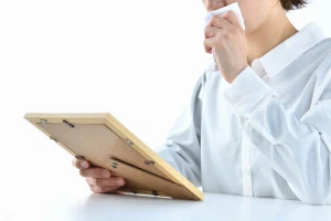 ペットの写真を見て悲しむ女性の写真