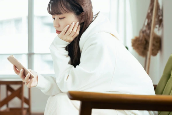 スマホ見て浮かない顔をしている女性の写真